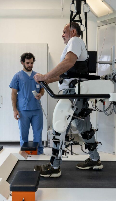 Senior Latin American man walking with an exoskeleton while doing physiotherapy after an injury